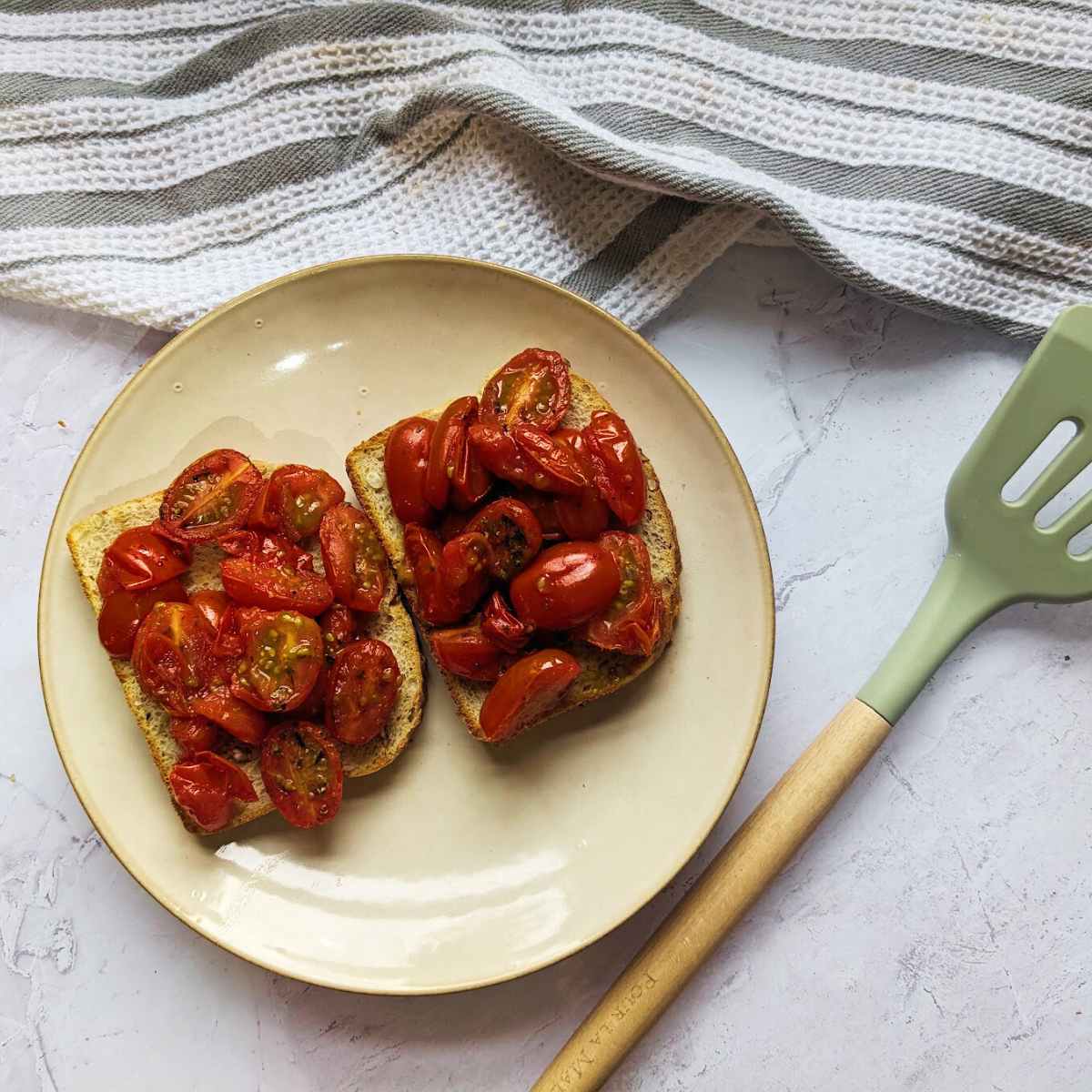 Roasted tomatoes on toast on a white plate