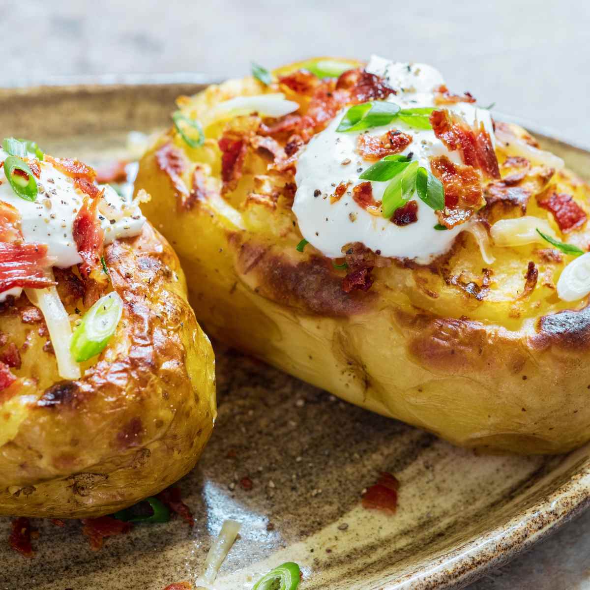 Baked potatoes with a bacon bits, spring onions and soured cream on top