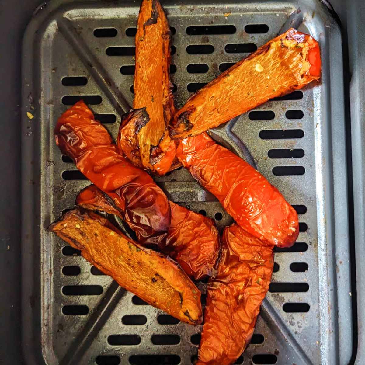 Sliced red bell peppers cooked in an air fryer basket