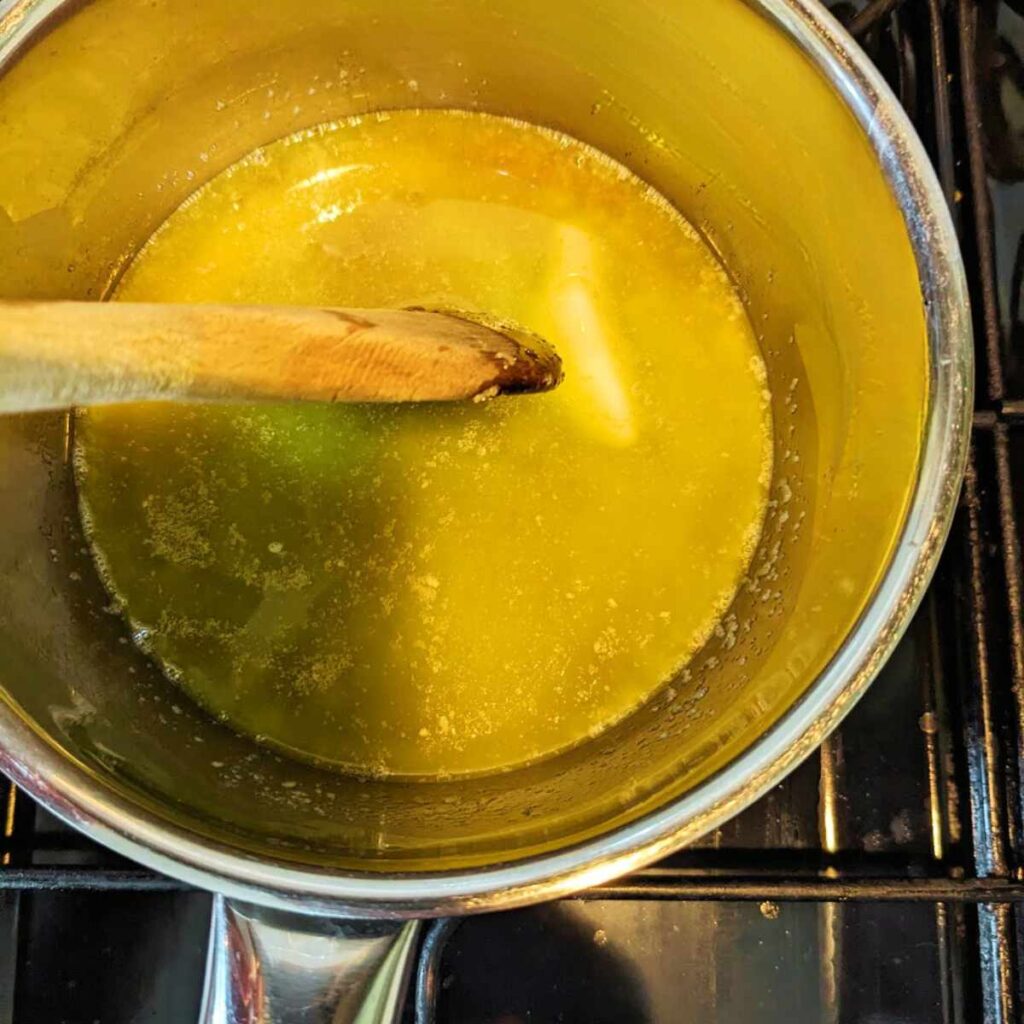 Butter and sugar melting in a pan with a wooden spoon.