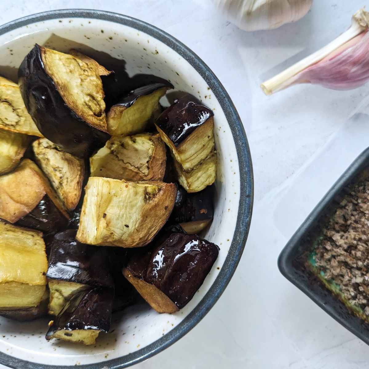 Air fryer aubergine in a bowl on a white board.