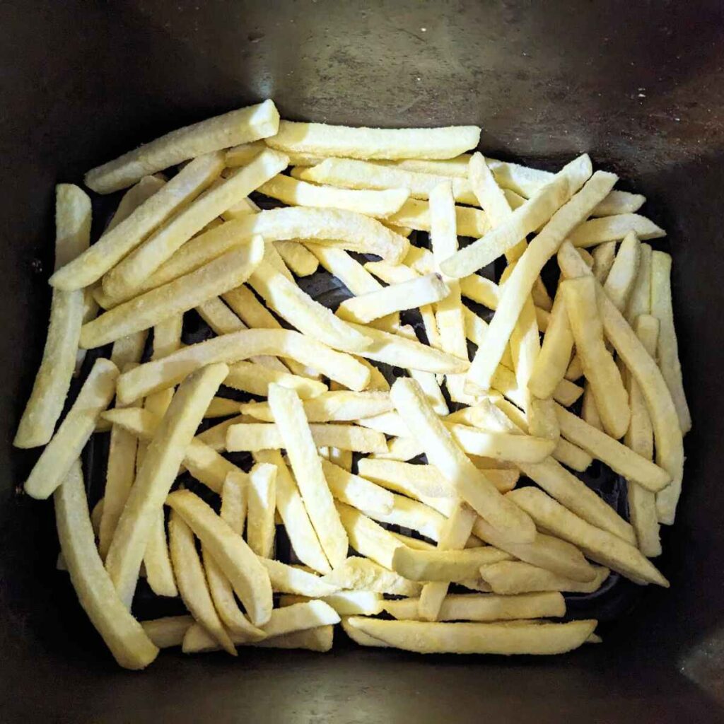 Frozen French fries in an air fryer basket