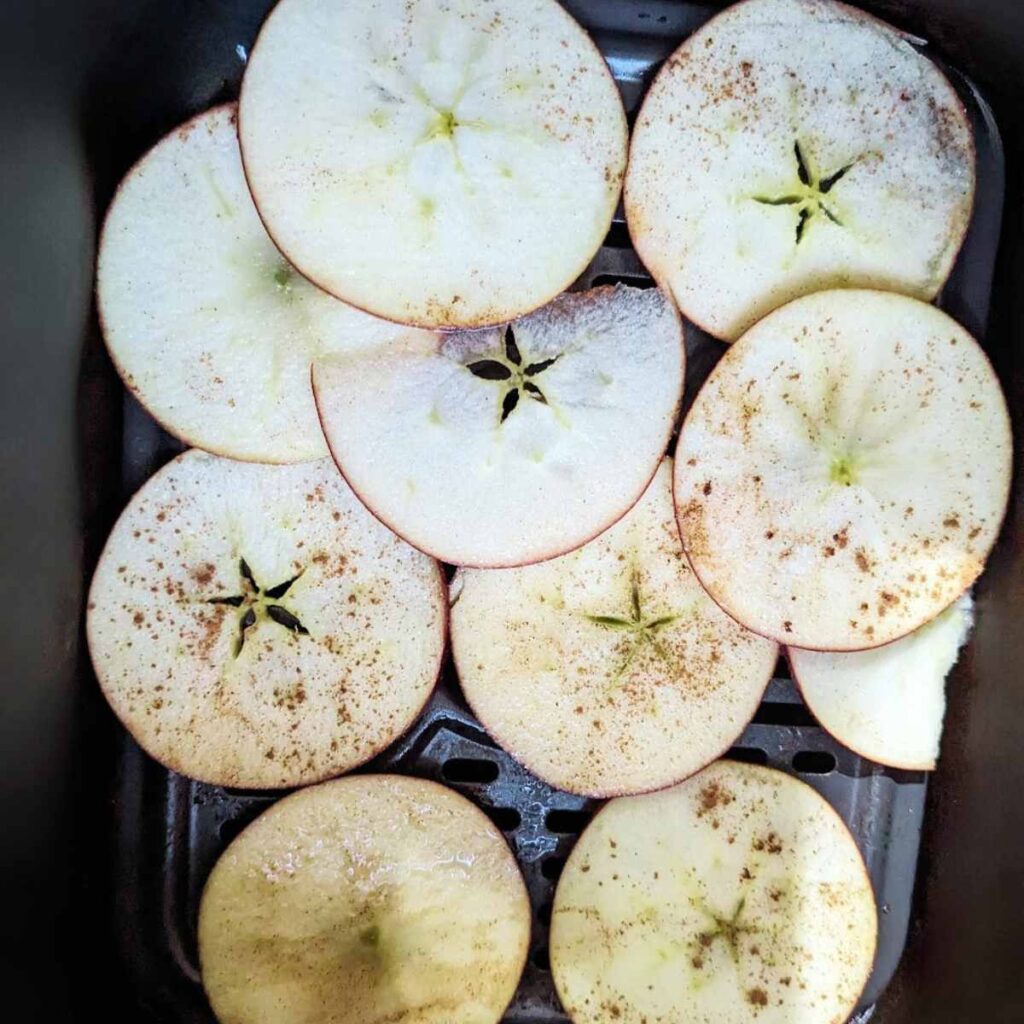 Apple slices in an air fryer basket.