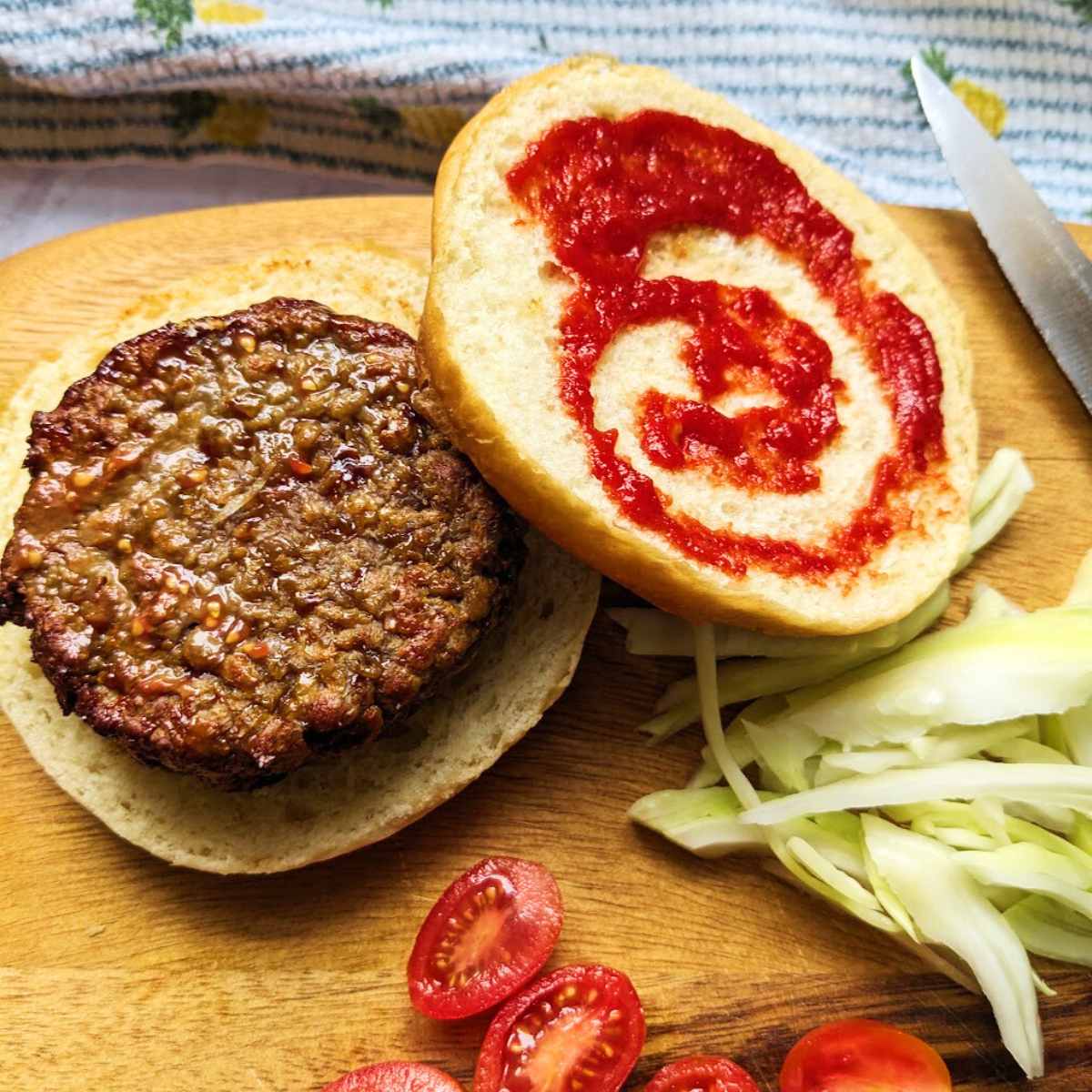 A Beyond Burger on a burger bun with a swirl of ketchup and salad ingredients at the side.
