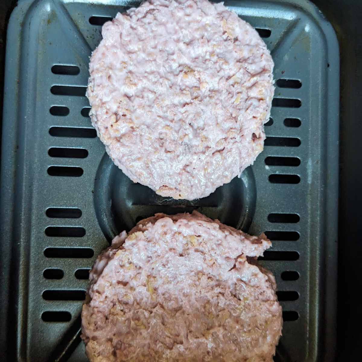 Two Beyond Burger patties in an air fryer basket.