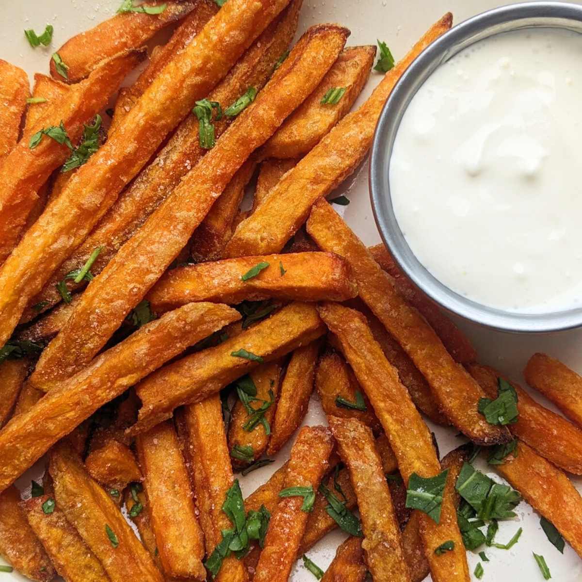 Sweet potato fries on a plate with a dipping sauce at the side.