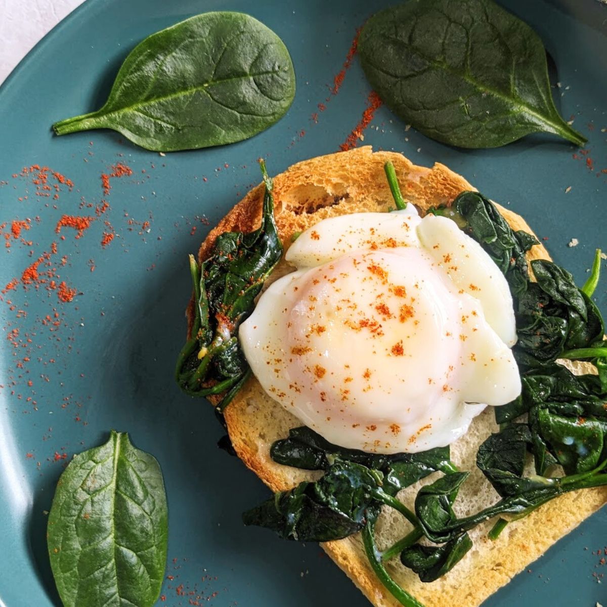 A poached egg on toast with wilted spinach.