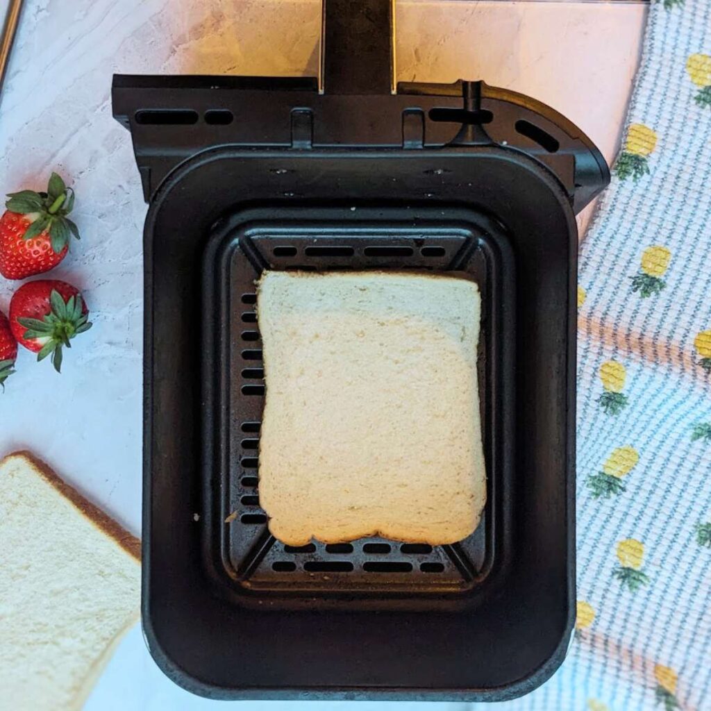 A slice of bread in an air fryer basket.