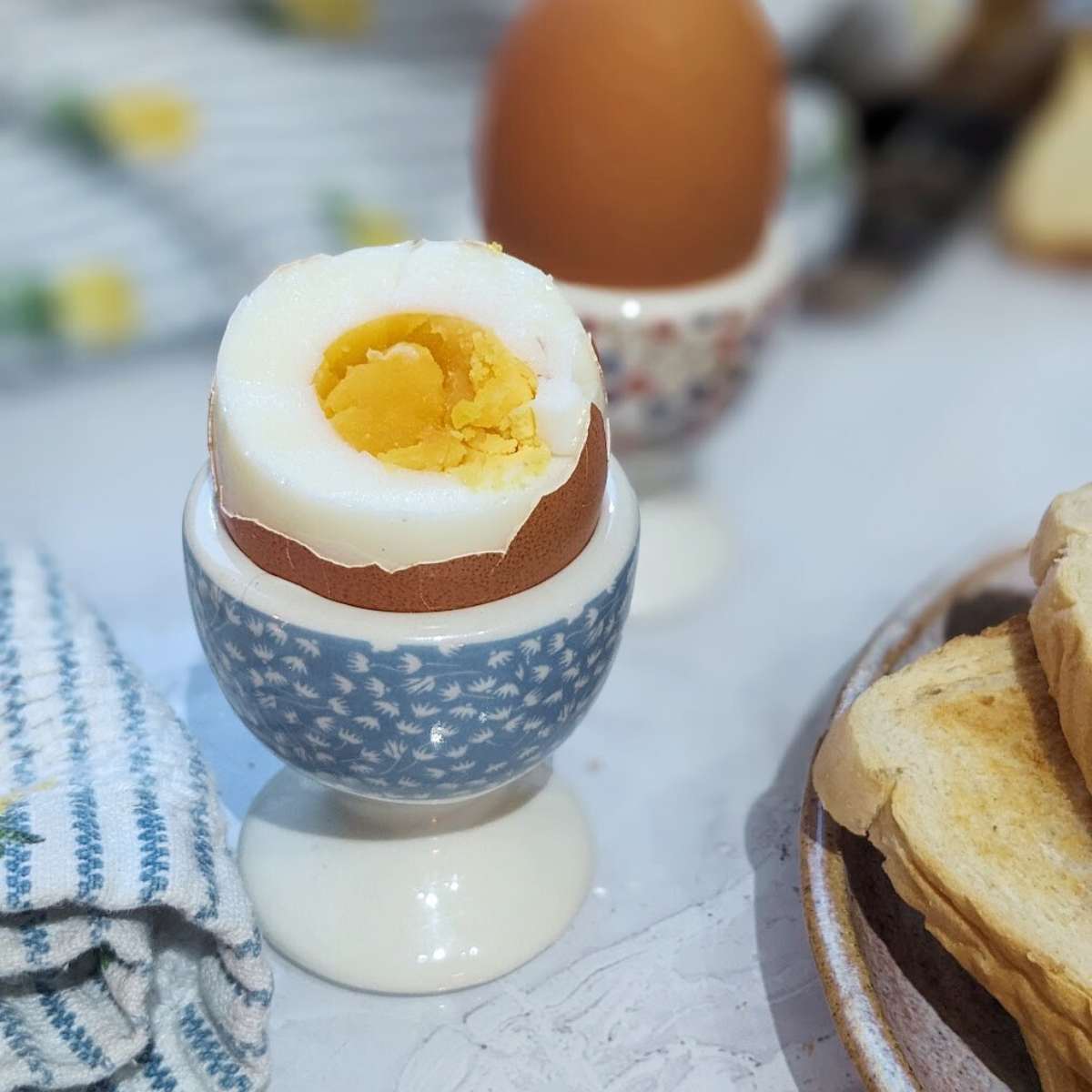 A hard boiled egg with part of the shell removed, served in an egg cup.