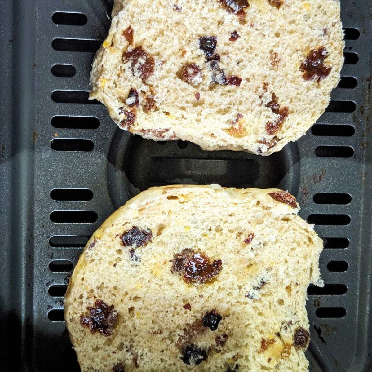 A sliced hot cross bun in air fryer basket.