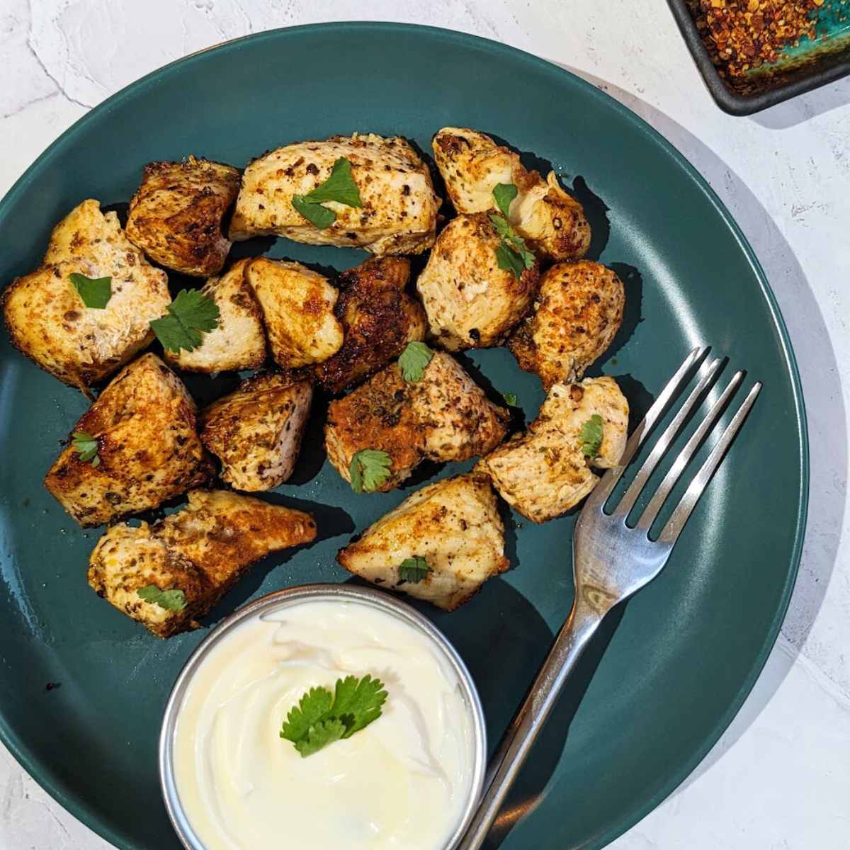 A plate of air fried chicken bites with a mayo dip on the side.
