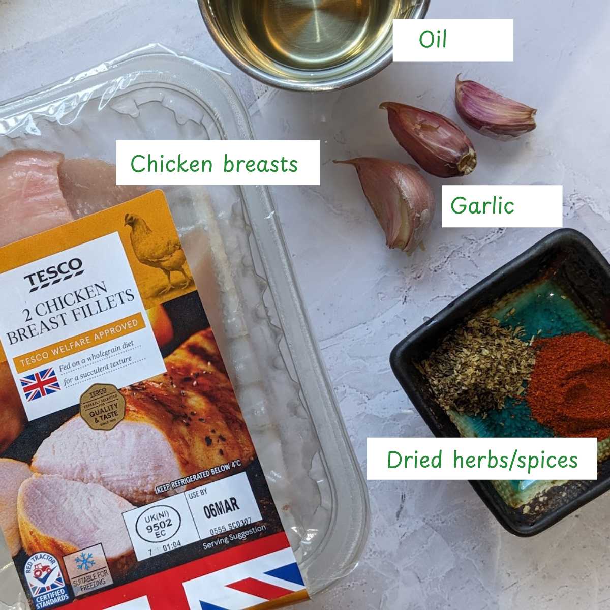 Ingredients for air fried chicken bites with chicken breasts, olive oil, garlic cloves and dried herbs.