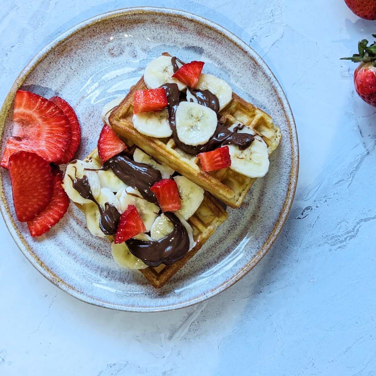 Waffles topped with banana, nutella and strawberries.