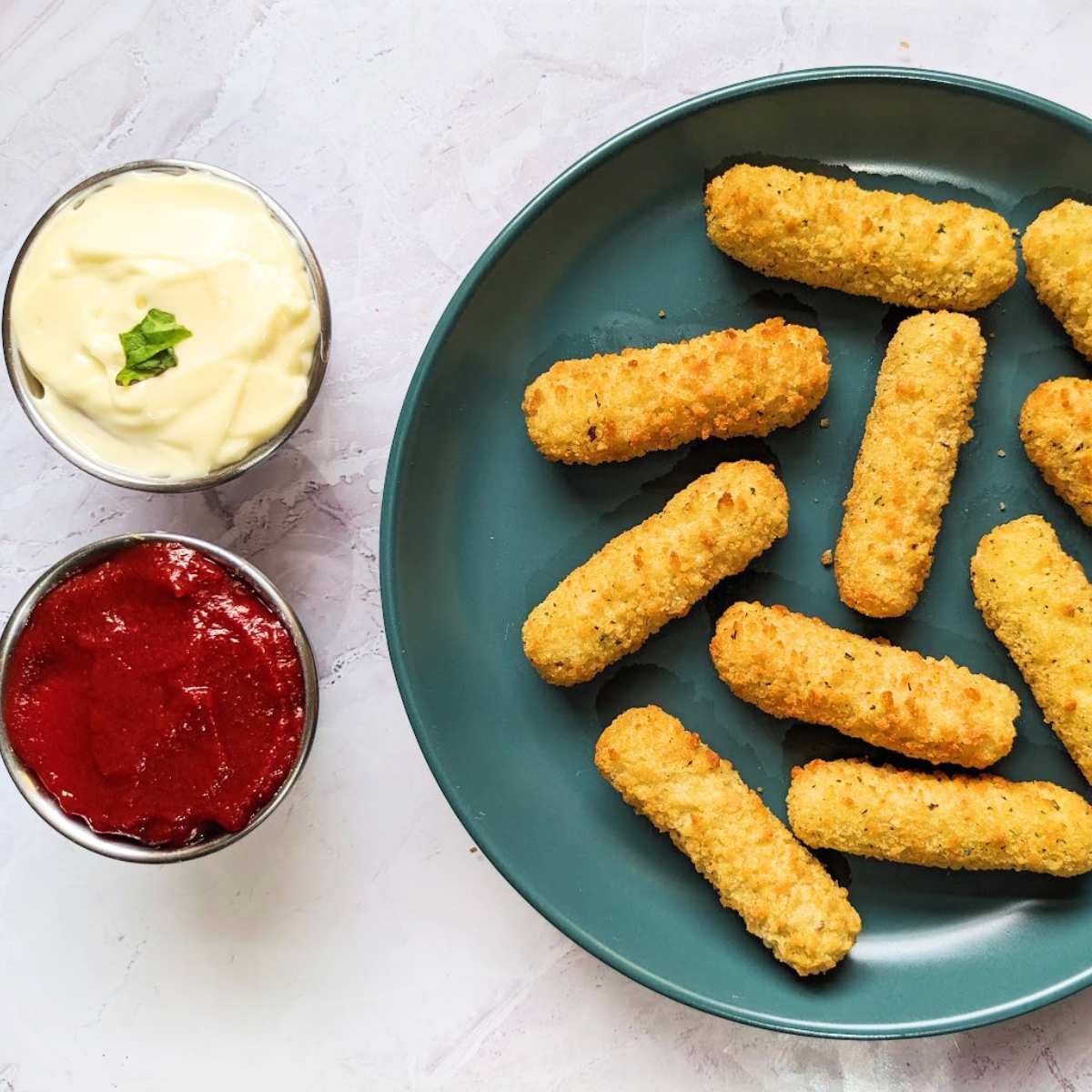 A plate of mozzarella sticks with mayo and ketchup dips on the side.