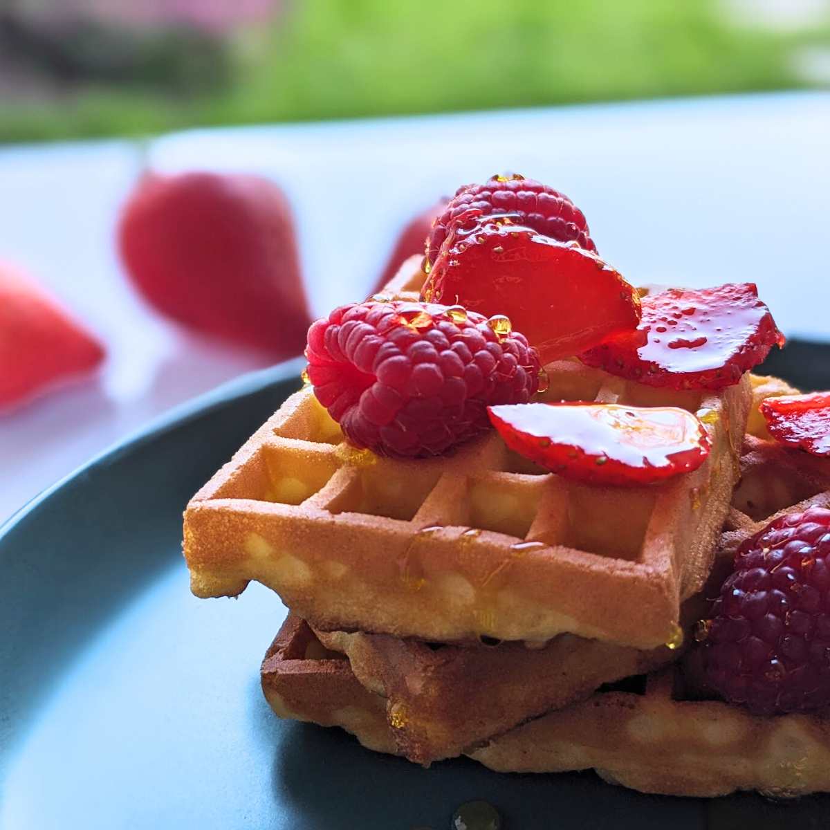 A stack of air fryer waffles topped with strawberries and a drizzle of honey.