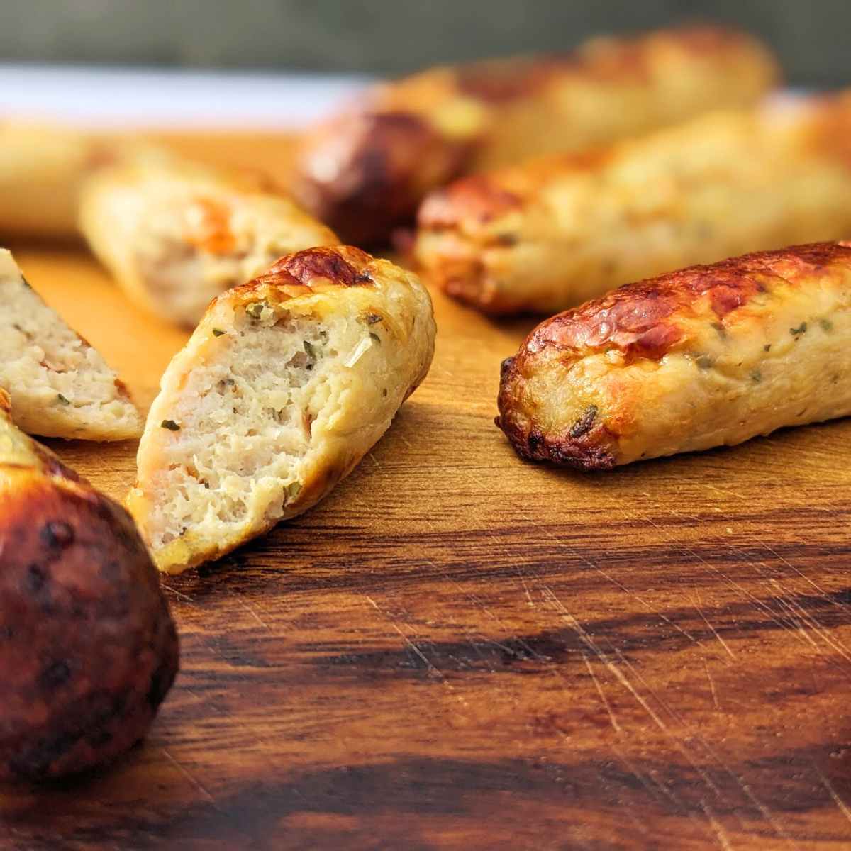 Sliced sausages and whole sausages on a board.