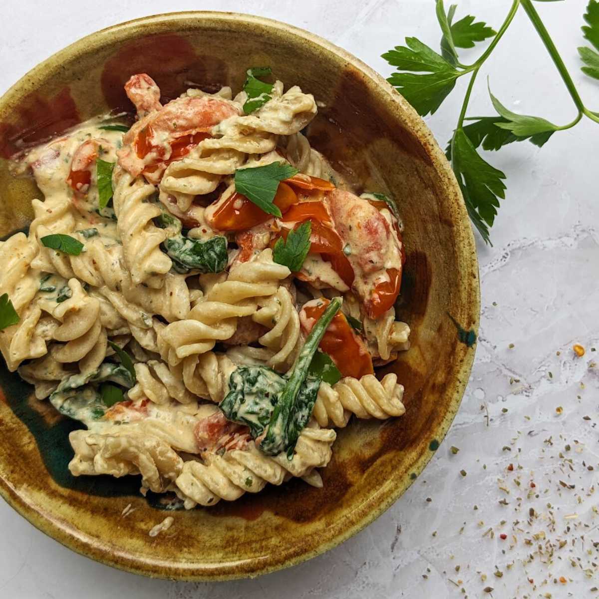 Boursin pasta in a bowl with cheese, tomatoes and spinach.