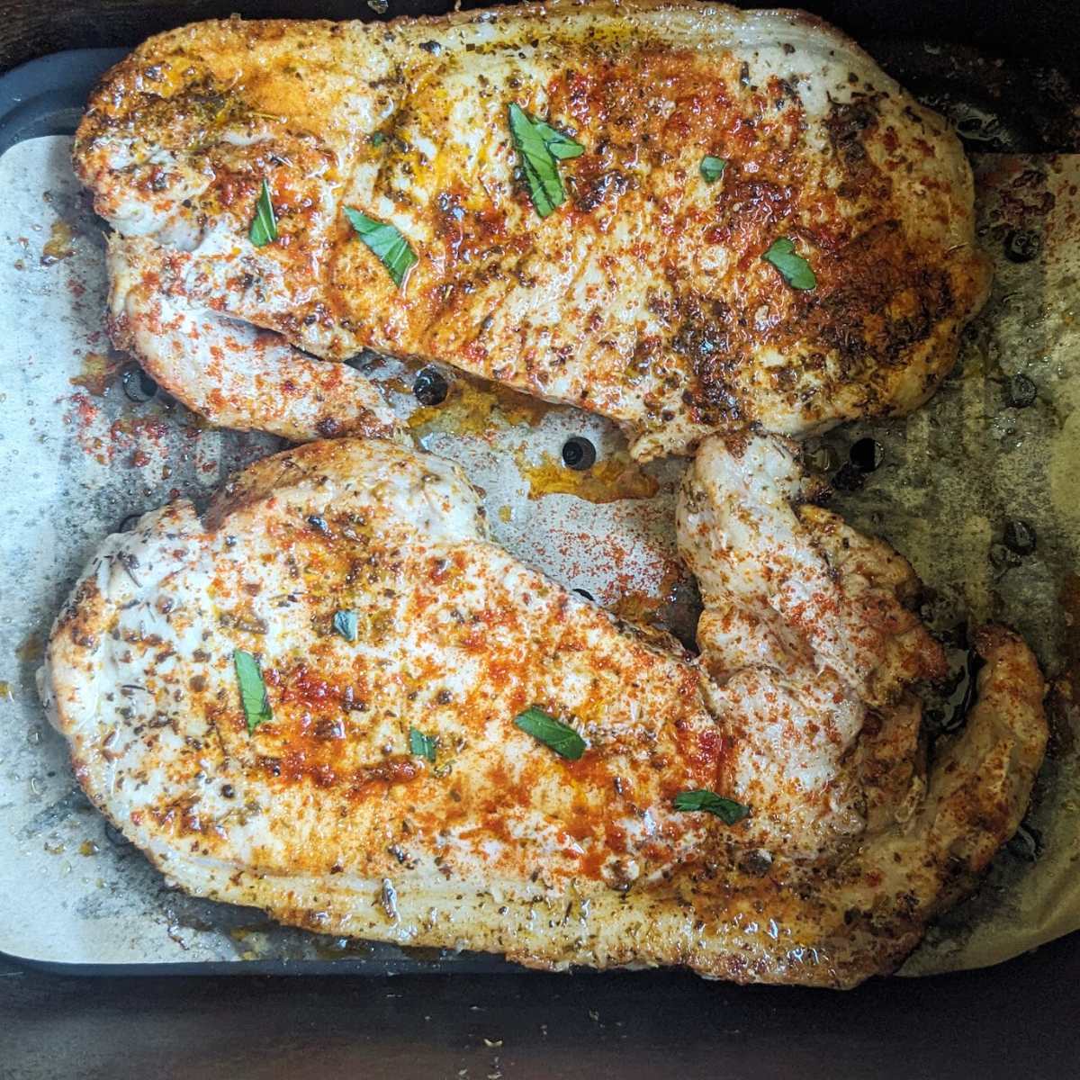 Two thin pork chops in an air fryer basket