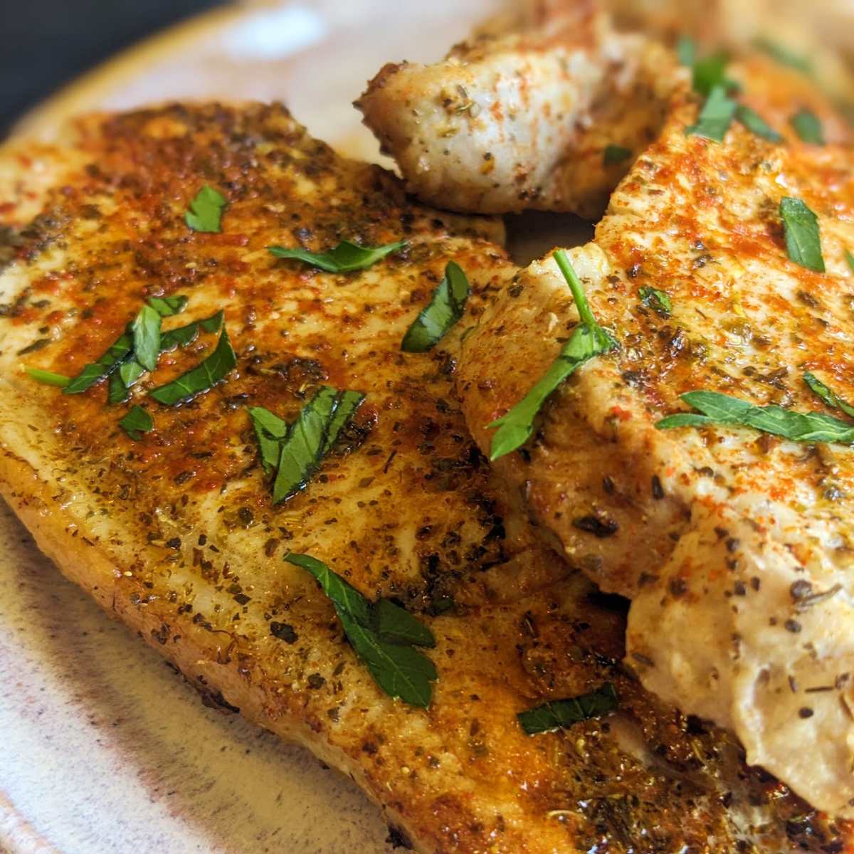 Thin pork chops cooked in air fryer and served on a plate.