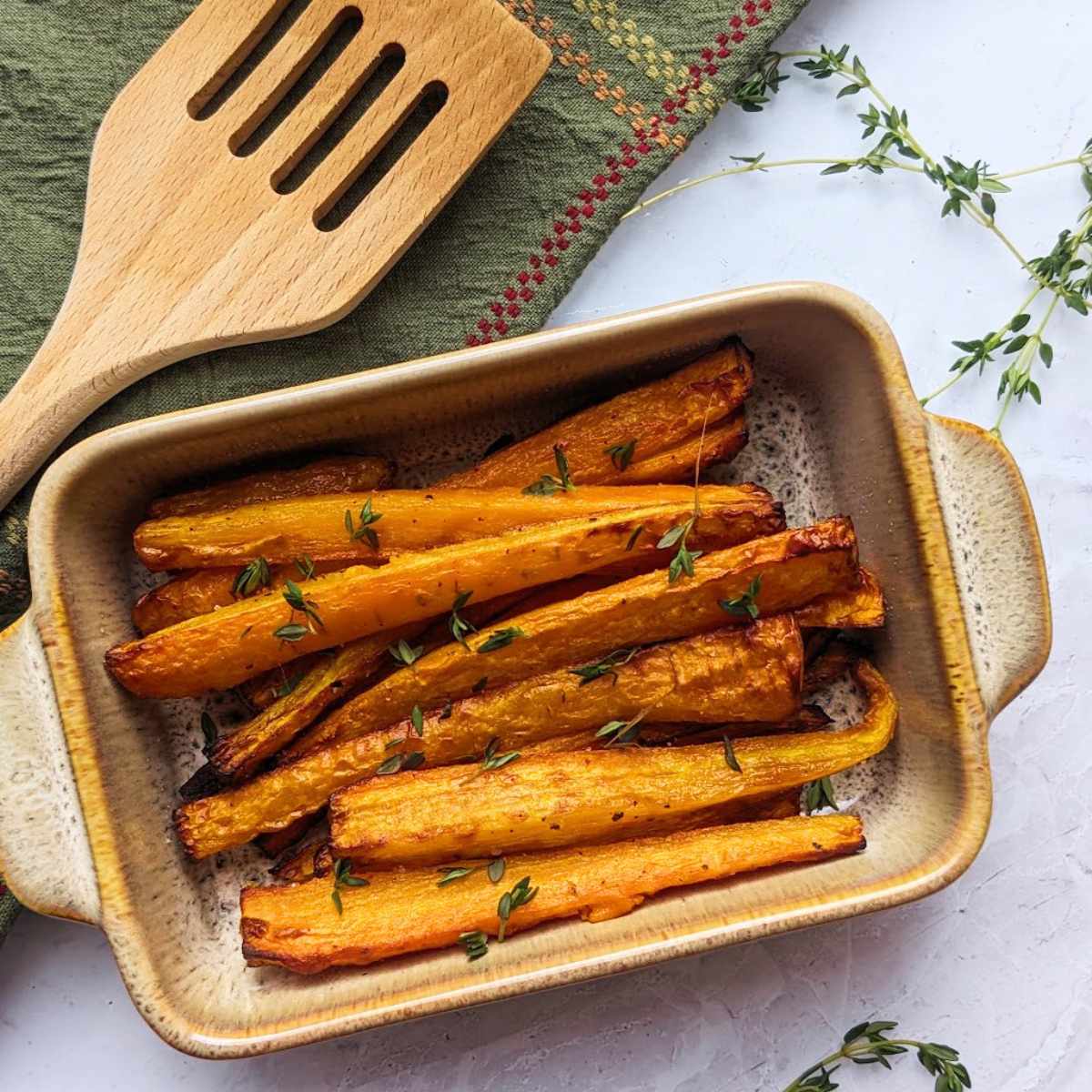 Air fryer roasted carrots in a serving dish with fresh herbs.