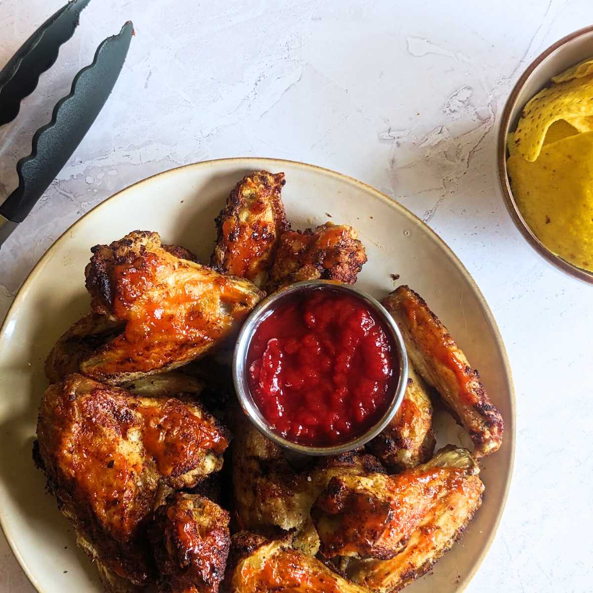 Chicken wings served on a plate with a tomato dip.