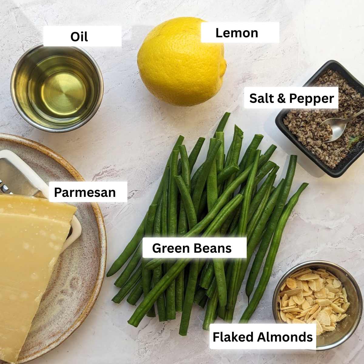 Ingredients for air fryer green beans including green beans, parmesan, oil, lemon, salt and pepper and flaked almonds.