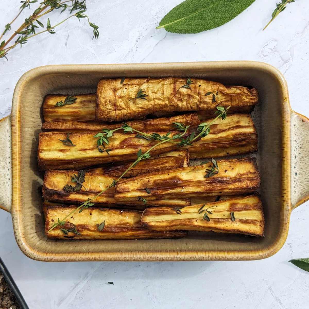 Air fryer parsnips in a serving dish with fresh herbs scattered on top.