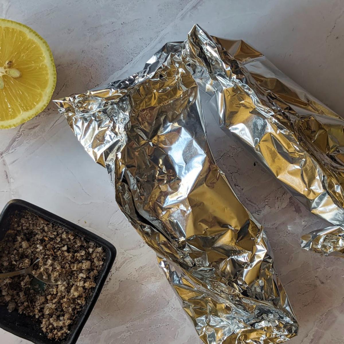 Two foil parcels on a kitchen worktop.