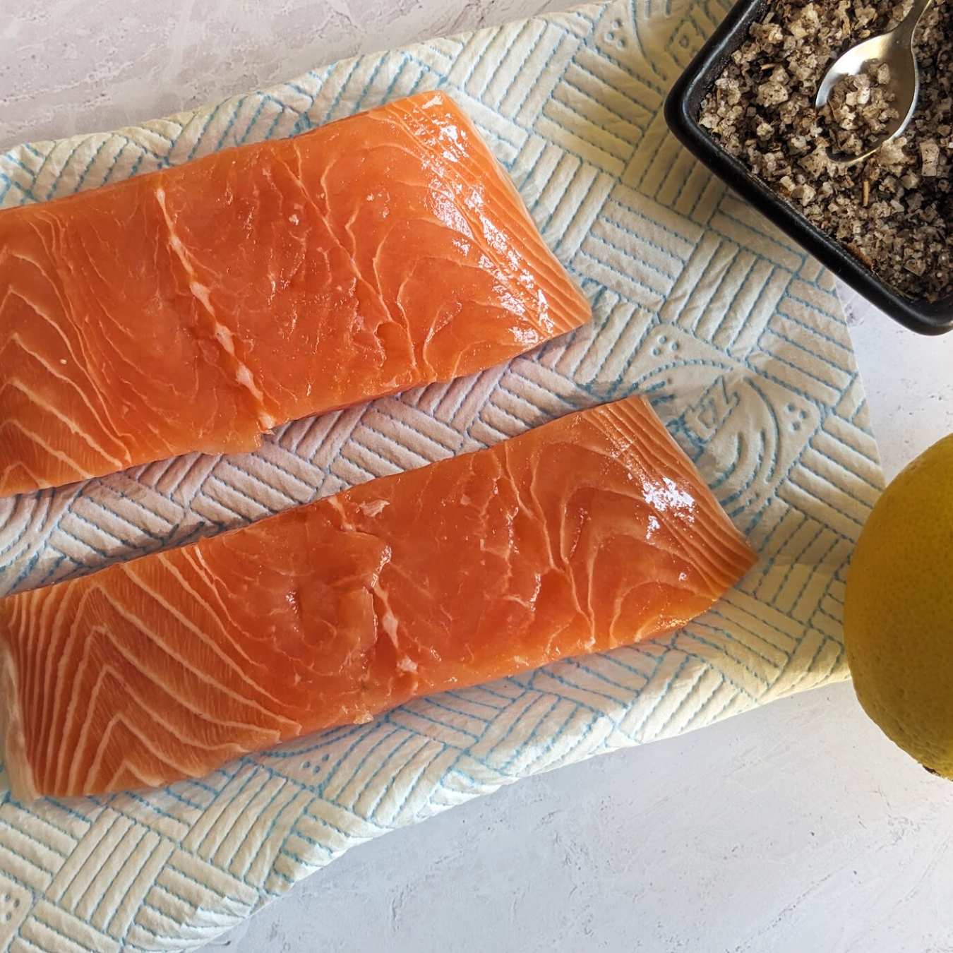 Two salmon fillets on a piece of kitchen paper.