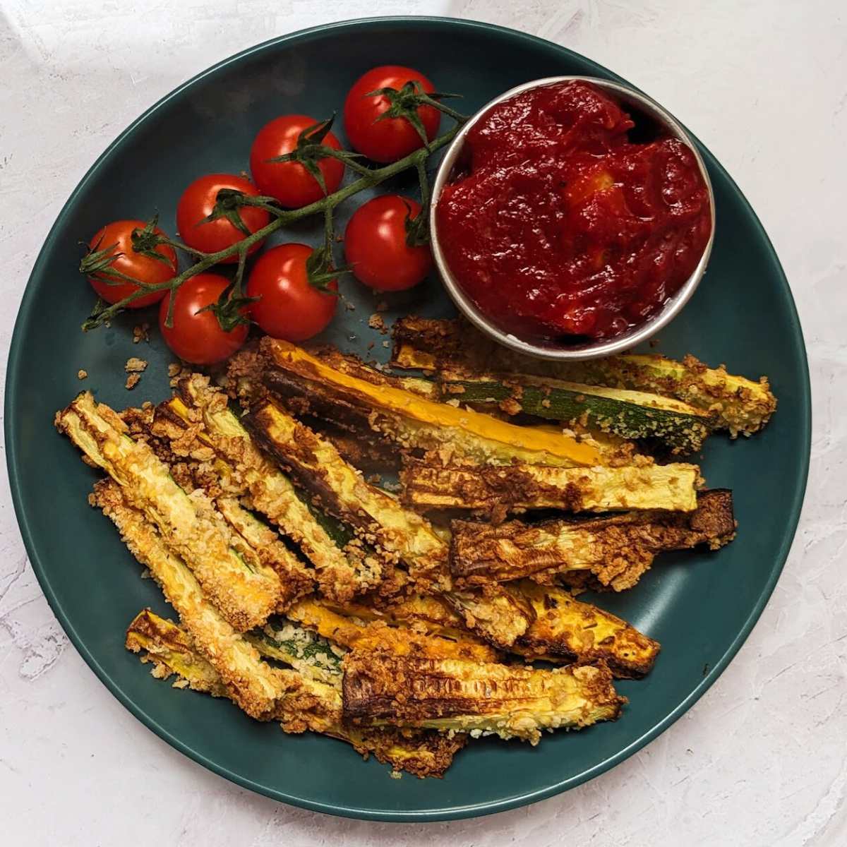 A plate of zucchini fries with a tomato dip.