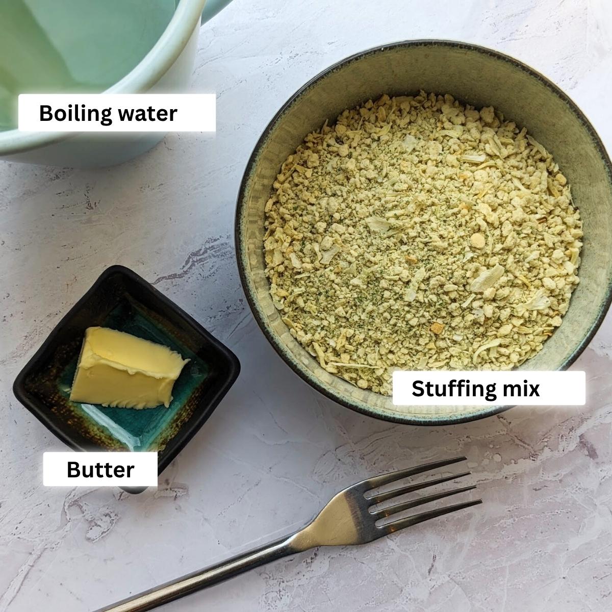 Ingredients for air fryer stuffing including stuffing mix in a bowl, a pat of butter and a jug of boiling water.