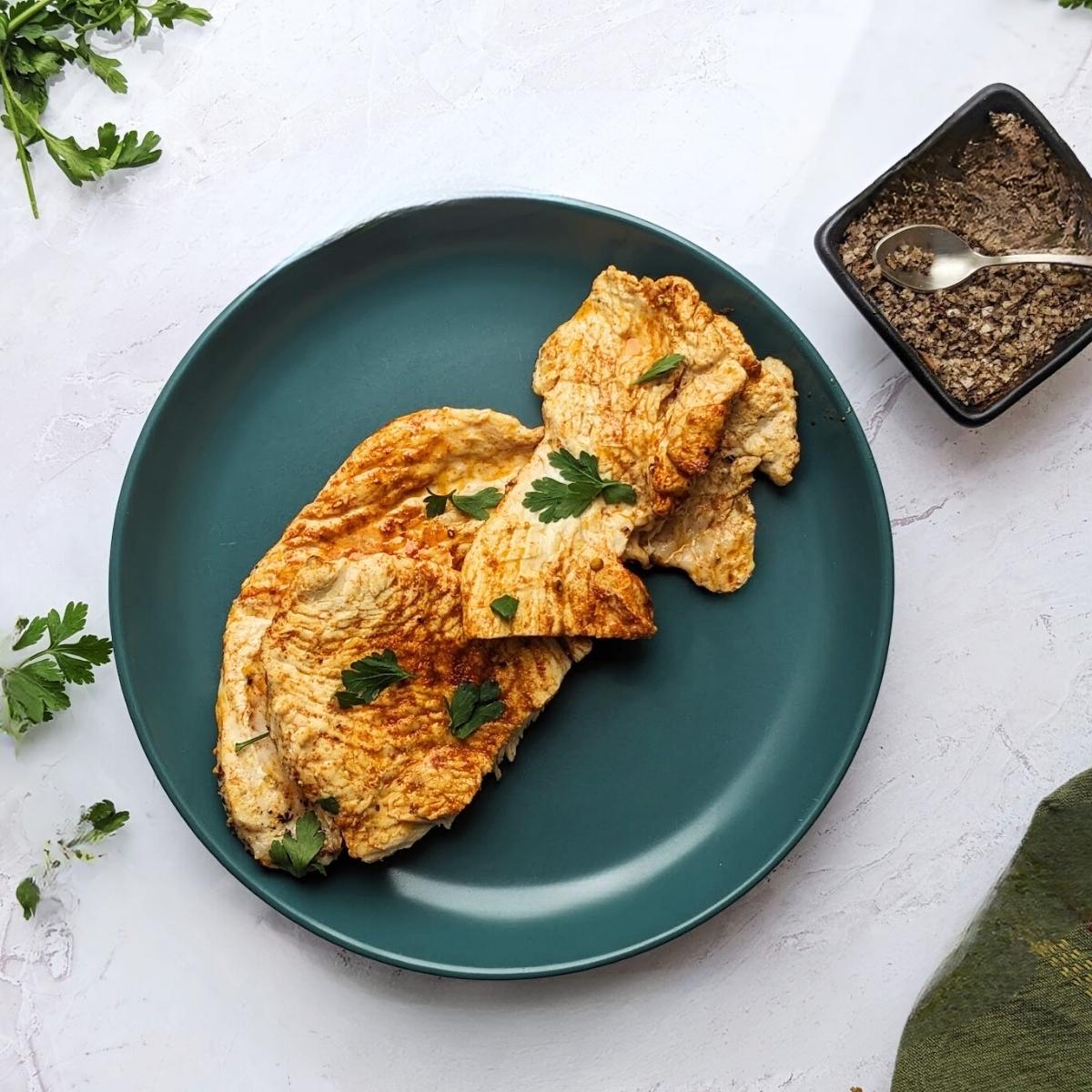Turkey steaks on a plate with herb garnish.