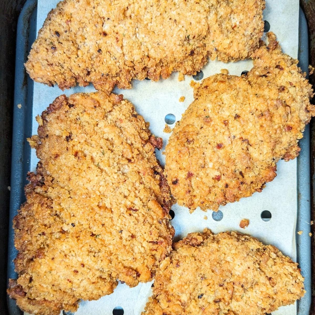 Chicken tenders on an air fryer basket.