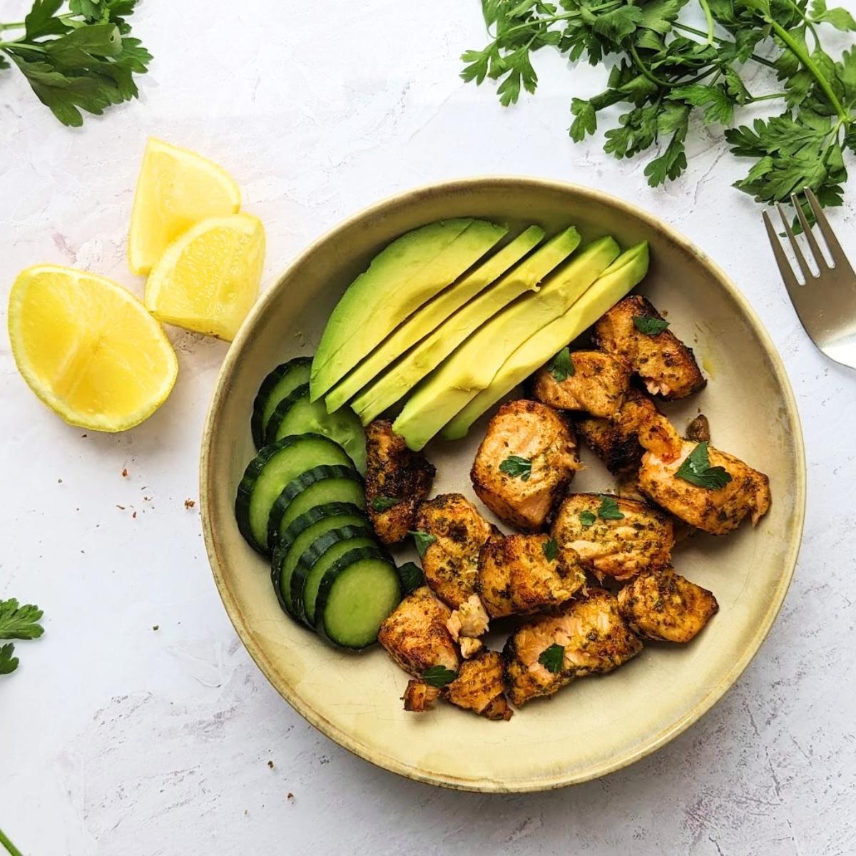 Air fryer salmon bites in a bowl with avocado and cucumber.