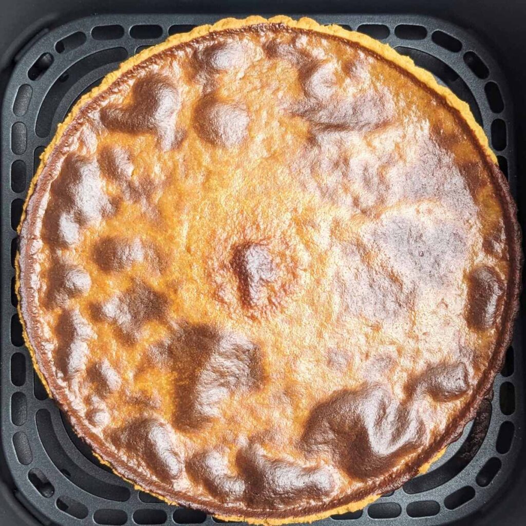 A cooked pumpkin pie in an air fryer basket.